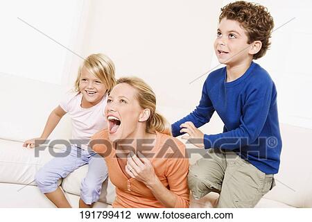 Woman playing with her son and a daughter in a living room View Large Photo Image Stock Image - Woman playing with her son and a daughter in a living room. Fotosearch