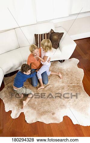 Woman playing with her son and a daughter in a living room View Large Photo Image Stock Photo - Woman playing with her son and a daughter in a living room. Fotosearch