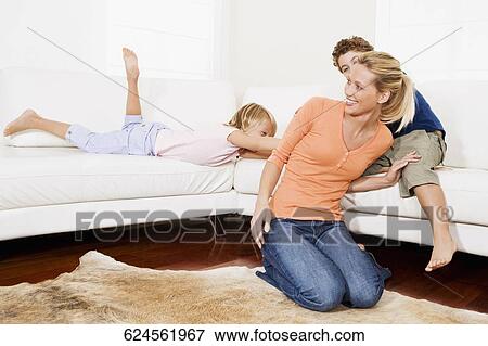 Woman playing with her son and a daughter in a living room View Large Photo Image Stock Photo - Woman playing with her son and a daughter in a living room. Fotosearch