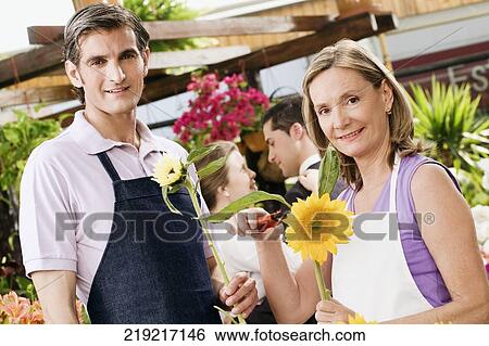 Woman pruning flowers with a man standing beside her View Large Photo Image Stock Photograph - Woman pruning flowers with a man standing beside her. Fotosearch