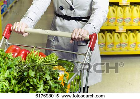 Woman pushing a shopping cart of vegetables View Large Photo Image Stock Photography - Woman pushing a shopping cart of vegetables. Fotosearch