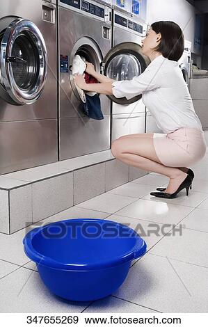 Woman putting clothes into a washing machine View Large Photo Image Stock Photo - Woman putting clothes into a washing machine. Fotosearch