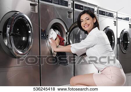 Woman putting clothes into a washing machine View Large Photo Image Stock Photo - Woman putting clothes into a washing machine. Fotosearch