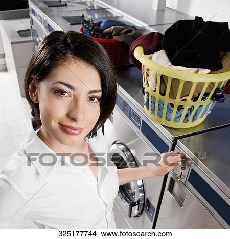 Woman putting coin into a washing machine View Large Photo Image Picture - Woman putting coin into a washing machine. Fotosearch