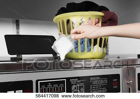 Stock Photo - Woman putting detergent into a washing machine. Fotosearch