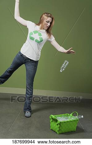 Picture - Woman putting plastic bottles into a recycling bin. Fotosearch