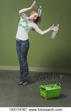 Woman putting plastic bottles into a recycling bin View Large Photo Image Stock Photo - Woman putting plastic bottles into a recycling bin. Fotosearch
