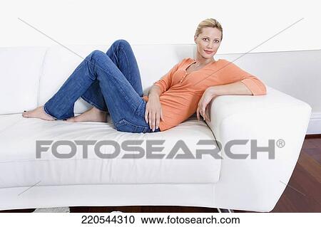 Woman reclining on a couch and smiling View Large Photo Image Stock Image - Woman reclining on a couch and smiling. Fotosearch