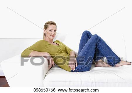 Woman reclining on a couch and smiling View Large Photo Image Stock Photograph - Woman reclining on a couch and smiling. Fotosearch