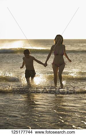 Picture - Woman running with her son on the beach. Fotosearch