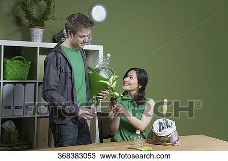 Stock Image - Woman showing a seedling to a man. Fotosearch