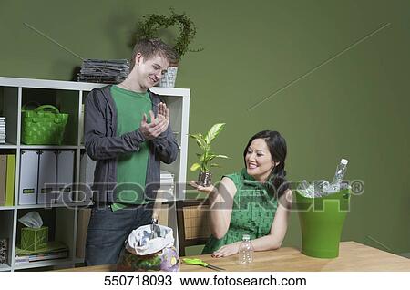 Stock Image - Woman showing a seedling to a man clapping beside her. Fotosearch