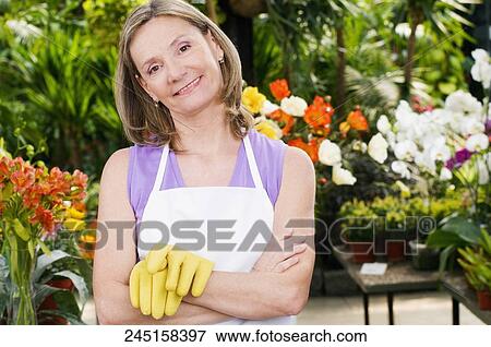 Woman standing in a greenhouse View Large Photo Image Stock Photo - Woman standing in a greenhouse. Fotosearch