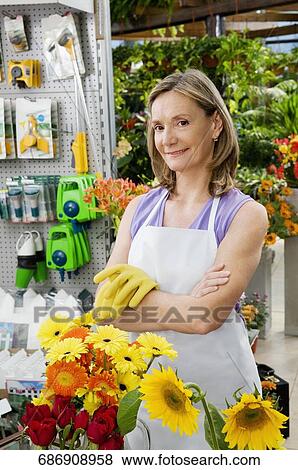 Stock Photo - Woman standing in a greenhouse. Fotosearch