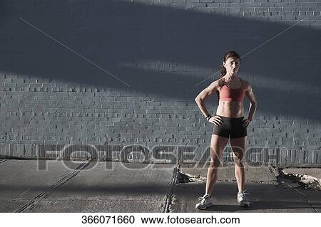 Stock Image - Woman standing with arms akimbo. Fotosearch