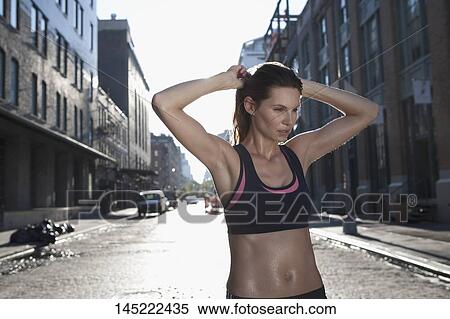 Stock Photography - Woman standing with her hands behind head. Fotosearch