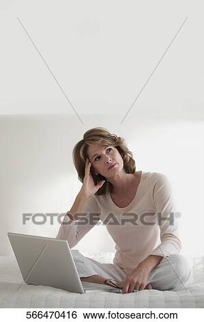 Woman working on a laptop and thinking View Large Photo Image Stock Photograph - Woman working on a laptop and thinking. Fotosearch