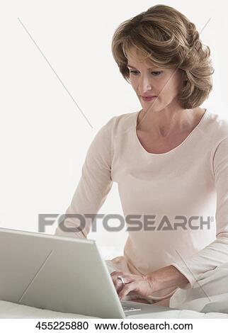 Woman working on a laptop on the bed View Large Photo Image Stock Image - Woman working on a laptop on the bed. Fotosearch
