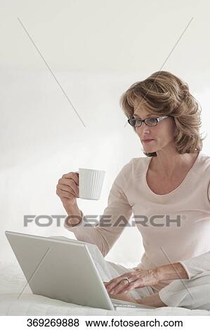 Woman working on a laptop on the bed View Large Photo Image Stock Photo - Woman working on a laptop on the bed. Fotosearch