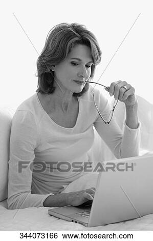 Woman working on a laptop on the bed View Large Photo Image Stock Photograph - Woman working on a laptop on the bed. Fotosearch