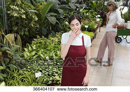 Stock Photo - Woman yawning in a greenhouse. Fotosearch