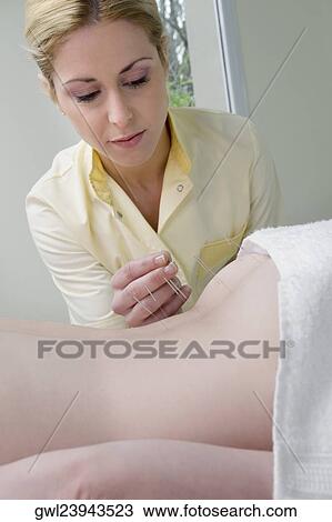 Acupuncturist applying needles on a person's back View Large Photo Image Stock Image - Acupuncturist applying needles on a person's back. Fotosearch