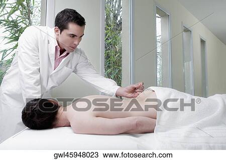 Acupuncturist applying needles on a person's back View Large Photo Image Stock Image - Acupuncturist applying needles on a person's back. Fotosearch