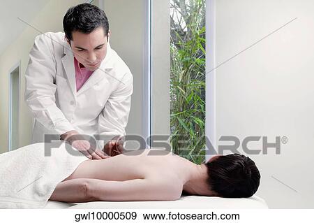 Acupuncturist applying needles on a person's back View Large Photo Image Stock Photo - Acupuncturist applying needles on a person's back. Fotosearch