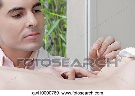 Acupuncturist applying needles on a person's back View Large Photo Image Stock Photo - Acupuncturist applying needles on a person's back. Fotosearch
