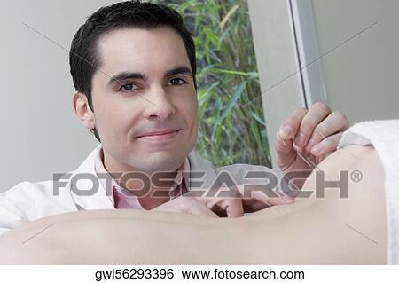 Acupuncturist applying needles on a person's back View Large Photo Image Stock Photograph - Acupuncturist applying needles on a person's back. Fotosearch