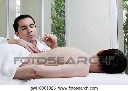 Stock Photography - Acupuncturist applying needles on a person's back. Fotosearch