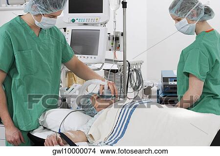 Picture - Anesthetist using an oxygen mask on a patient in a hospital. Fotosearch