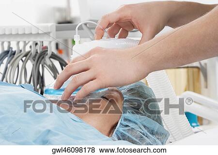 Anesthetist using an oxygen mask on a patient in a hospital View Large Photo Image Stock Photo - Anesthetist using an oxygen mask on a patient in a hospital. Fotosearch