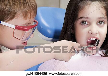 Boy imitating as a dentist and examining a girl's teeth View Large Photo Image Stock Photography - Boy imitating as a dentist and examining a girl's teeth. Fotosearch