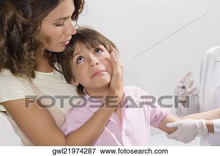 Boy looking at his mother while a doctor injecting him View Large Photo Image Stock Photo - Boy looking at his mother while a doctor injecting him. Fotosearch