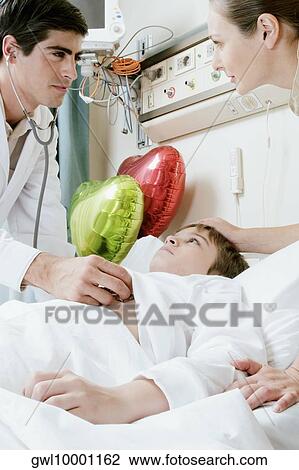 Boy on a hospital bed being examined by a doctor View Large Photo Image Stock Image - Boy on a hospital bed being examined by a doctor. Fotosearch
