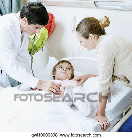 Boy on a hospital bed being examined by a doctor View Large Photo Image Stock Photo - Boy on a hospital bed being examined by a doctor. Fotosearch