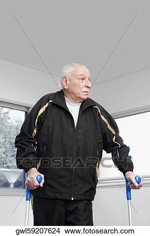Picture - Close-up of a disabled man walking with crutches. Fotosearch