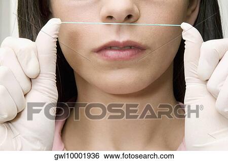 Stock Photograph - Close-up of a female doctor holding dental floss. Fotosearch