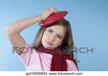 Stock Image - Close-up of a girl applying ice pack on her head. Fotosearch