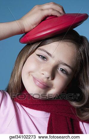 Stock Image - Close-up of a girl applying ice pack on her head. Fotosearch