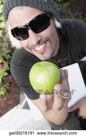 Stock Image - Close-up of a man holding a granny smith apple. Fotosearch
