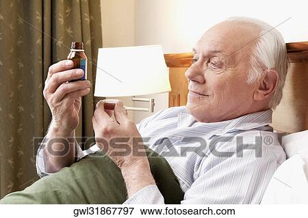 Close-up of a man taking medicine View Large Photo Image Stock Photo - Close-up of a man taking medicine. Fotosearch