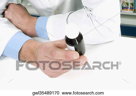 Close-up of a pharmacist's hand holding a vial of medicine View Large Photo Image Stock Image - Close-up of a pharmacist's hand holding a vial of medicine. Fotosearch