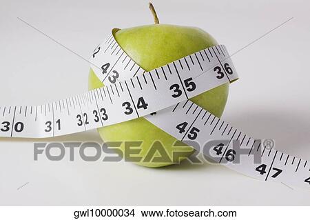 Close-up of a tape measure wrapped around a green apple View Large Photo Image Picture - Close-up of a tape measure wrapped around a green apple. Fotosearch