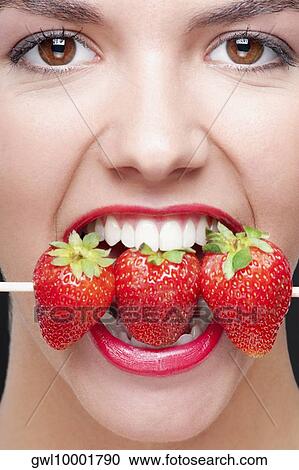 Close-up of a woman biting strawberries on a skewer View Large Photo Image Stock Image - Close-up of a woman biting strawberries on a skewer. Fotosearch