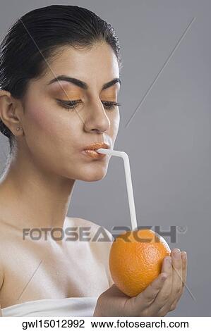 Close-up of a woman drinking from a straw in an orange View Large Photo Image Stock Image - Close-up of a woman drinking from a straw in an orange. Fotosearch