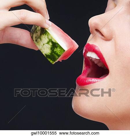 Stock Photography - Close-up of a woman eating a watermelon slice. Fotosearch
