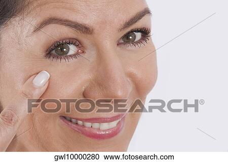 Stock Image - Close-up of a woman examining her face. Fotosearch