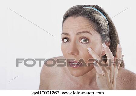 Stock Image - Close-up of a woman examining her face. Fotosearch